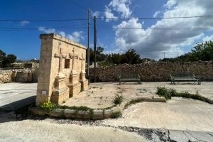A standalone small wall in the middle of the countryside with three crosses on it
