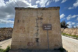 A blank wall with a plaque reading "the Three Crosses"