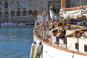 An old style white sailboat with people on deck