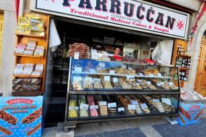 A sweet shop with a sign reading "Parruccan" and a display of traditional Maltese sweets in a colorful array.