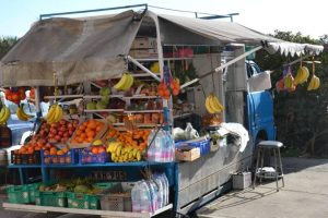 A local farmer selling produce from a stand perched on the back of an open car