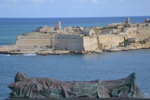 A statue of a lying soldier at the bottom of the screen with a view of a peninsula in the background