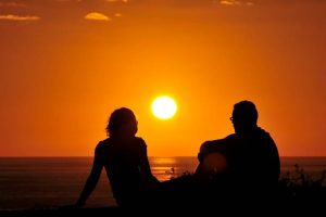 A sunset silhouette of a couple overlooking the beach near the Blue Grotto View Point.