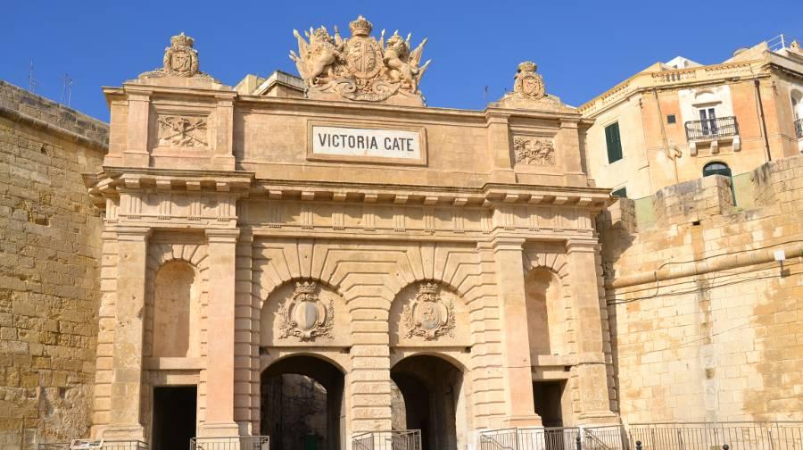 Victoria Gate in Valletta Victoria Gate in Valletta as seen from ground level. An intricate limestone wall with a crest atop an arch-like construction and a sign that reads "Victoria Gate"