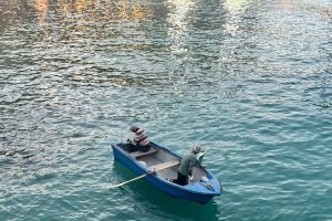 A simple fishing boat in Balluta Bay with two men atop